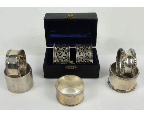 A pair of Edward VII hallmarked silver circular pierced decorated napkin rings with initialled shield shaped cartouche, EJ Tr