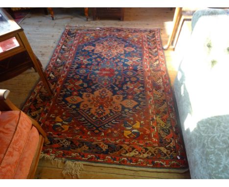 A Middle Eastern carpet, profusely patterned throughout on a blue, salmon pink and black ground (194 x 138cm).