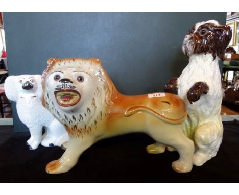 A large Staffordshire ceramic model of a lion, painted mouth and glass eyes, together with two further Staffordshire dogs.
