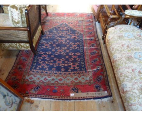 A Middle Eastern carpet, the central temple shaped blue lozenge bordered by repeating geometric shapes (208cm x 143).