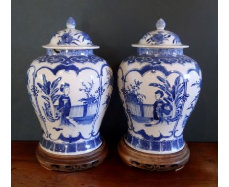 A pair of late 19th century Chinese blue and white jars and covers, each decorated with reserves depicting figures in a garde