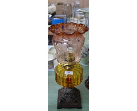 An iron base oil lamp with amber bowl and etched red glass shade