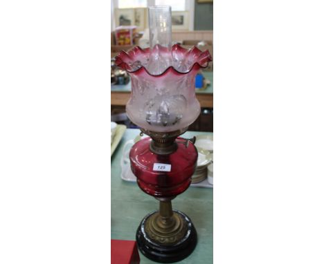 A brass column oil lamp with cranberry bowl and etched pink glass shade