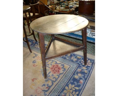 An Oak circular topped Cricket Table, the triple legs united by a triangular galleried shelf, 27 1/2'' diameter, 26 3/4'' hig