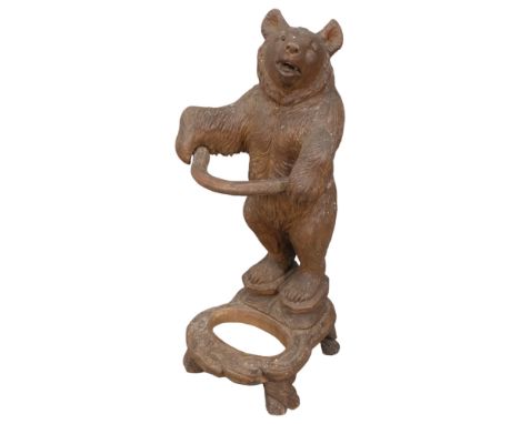 A late 19th century German Black Forest bear stick stand, modelled standing upright with original glass eyes, holding a branc