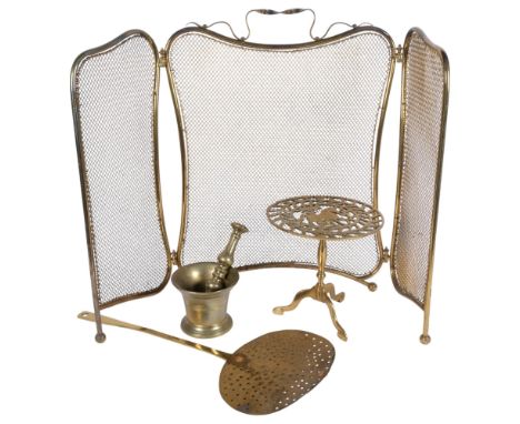 A 3-fold brass fire screen, a 19th century pestle and mortar, and a pierced trivet, and a brass skimmer 