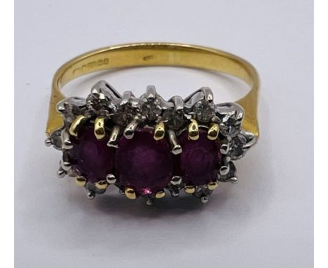 An 18ct gold Ruby and diamond cluster ring. featuring three mixed cut, oval shape rubies and 16 round brilliant cut diamonds.