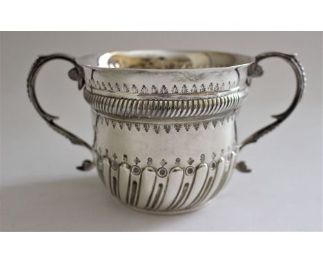 A Queen Anne style silver loving cup with partial wrythen moulding, twin foliate scrolling handles and oval vacant cartouche 