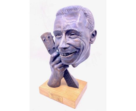 George Formby (1904-1961). A bronze bust of George Formby holding the neck of his banjo ukulele, by Graham High, on wooden st