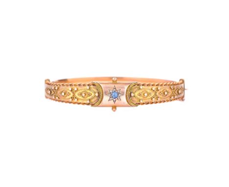 A 9ct gold, diamond and sapphire set oval hinged bangle, the front with a starburst shaped motif, centred by a cushion shaped