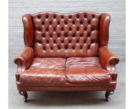 An 18th century style studded brown leather upholstered two seat wingback sofa on squat cabriole supports, 124cm wide x 96cm 
