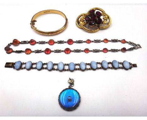 A Victorian gilt metal mounted red paste brooch, of scrolling openwork form, a gilt metal oval hinged bangle, with scroll eng
