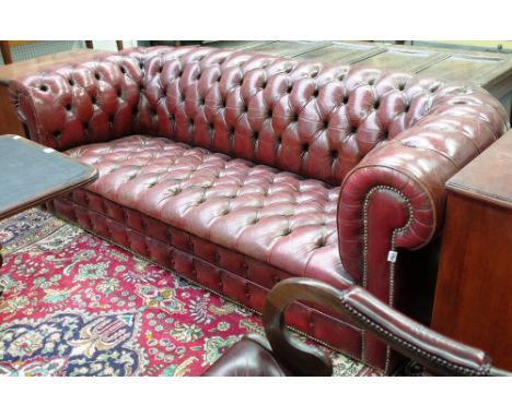 A brass studded rouge leather upholstered Chesterfield sofa, 20th century, 215cm wide x 70cm high. Illustrated 