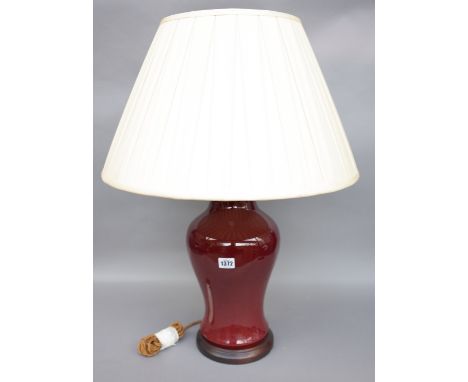 A Chinese porcelain vase table lamp, sang de boeuf, baluster ground with a cream silk pleated shade, vase 40.5cm high. 