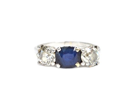 A diamond and sapphire three stone ring, claw set with an oval cut sapphire at the centre, between two cushion shaped diamond