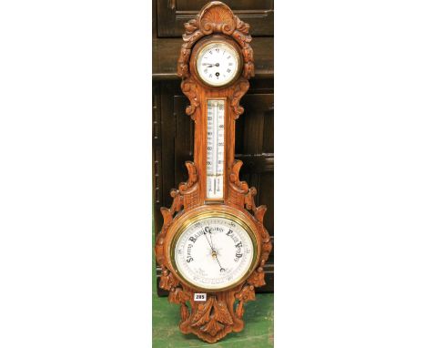 Victorian carved oak aneroid barometer with enamel dial clock above a thermometer and indicator dial, 90cm high.