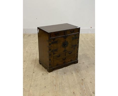 A Chinese style stained hardwood cabinet, fitted with four short and one long drawer, twin cupboard doors opening to paper li