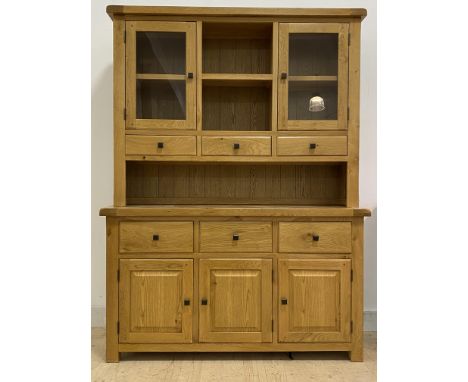 A contemporary oak dresser, the top fitted with open shelf flanked by two glazed cupboards, over three spice drawers, the bas