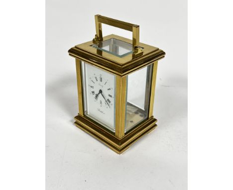 A Postilion quartz four glass clock with handle to top and enamel dial with roman numerals (h.14cm x 10cm x 8cm)