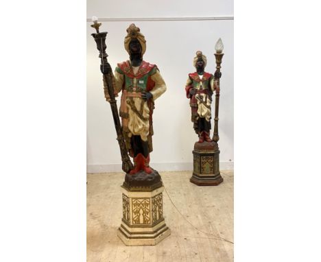 A matched pair of Moorish figural uplighters, moulded fibreglass in opposing positions holding a torch lamp holder, one with 