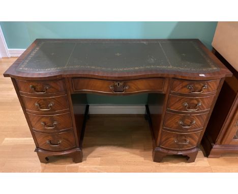 A mahogany serpentine fronted twin pedestal desk, the shaped top with inset leather skiver above central long drawer, flanked