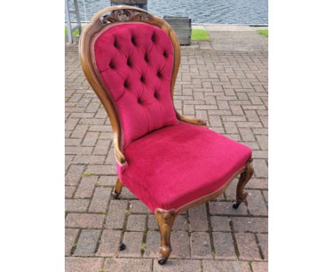 An Edwardian walnut nursing chair, scroll shape with button back velvet upholstery, upon cabriole legs with ceramic casters, 
