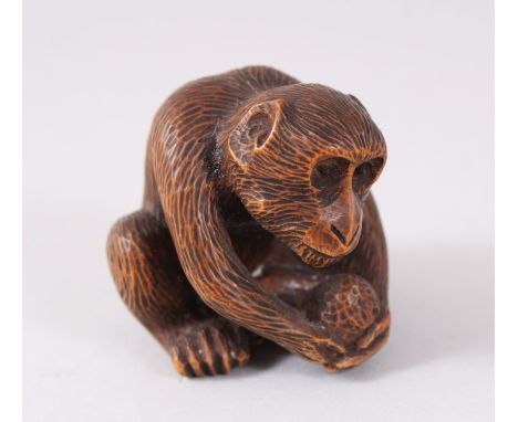 A GOOD QUALITY JAPANESE MEIJI PERIOD CARVED WOOD NETSUKE OF A MONKEY, sat down protecting his nut, eyes inlaid with horn, sig