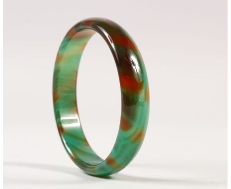 A CHINESE JADE LIKE GLASS BANGLE, of striated green and russet colouring, 7.9cm diameter.