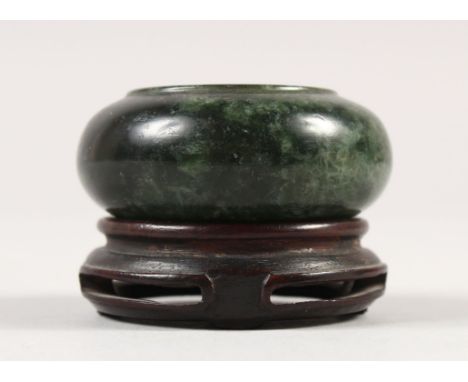 A SMALL CHINESE SPINACH GREEN JADE WATER POT, together with a fitted wood stand, the stone of predominantly dark tone with li