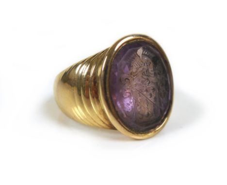 An amethyst intaglio inset within a 9ct gold signet ring, unmarked but tests as 9ct, with armorial engraving to amethyst, siz