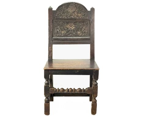 A Lancashire oak joined chair. 17/18th century, the arched panel back with floral and foliate carving, solid seat , on turned