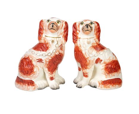 A pair of Staffordshire pottery spaniels. With russet patches, gilt collar padlock and chain, height 23cm. (2)