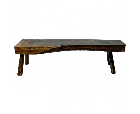 An elm low cobblers bench. 19th century, with primitive peg feet, height 25cm, width 90cm, depth 26cm.A very rustic piece wit