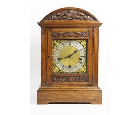 A late 19th/early 20th German oak cased bracket clock, by Mathias Bauerle, the arched case with a carved pediment above a 15c