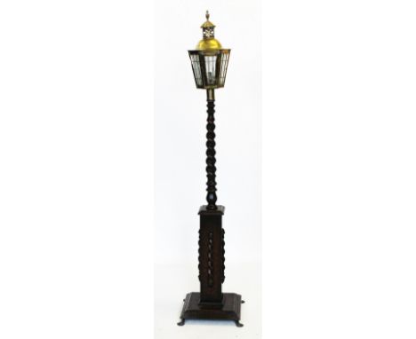 A 1920's oak standard lamp, with a brass lantern type shade of hexagonal tapering form, upon a oak barley twist column and a 