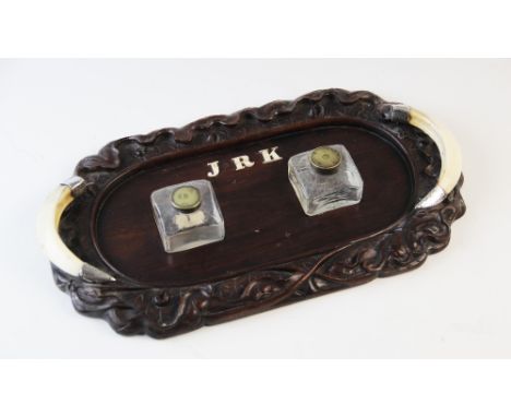A 19th century Anglo-Indian desk stand, the carved stand mounted with white metal, bone and boars tusk, supporting two campai