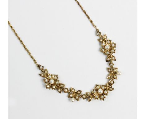 A Victorian style 9ct gold and split seed pearl set necklace, designed as three floral clusters, joined by foliate links, and