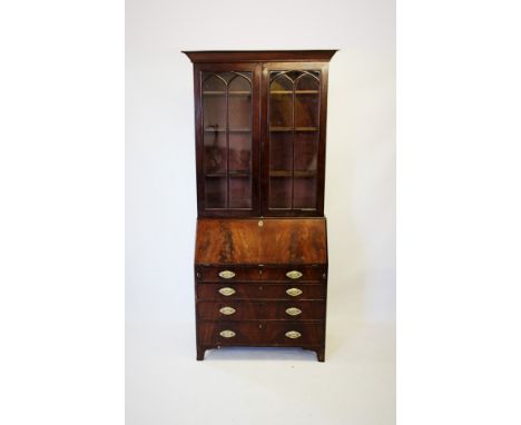 An early 19th century mahogany bureau bookcase, with a moulded tapering cornice above a pair of glazed doors, applied with Go