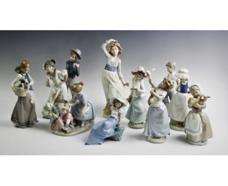 A Lladro figure of a girl holding a basket with three puppies, a Nao group, a young dancing couple, a Nao group, two young gi