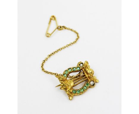 An emerald and seed pearl set lyre form brooch, all set in yellow metal, unmarked, attached safety chain, gross weight 2.2gms