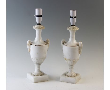 A pair of alabaster lamp bases, each of classical two handled urn form, raised on square plinth base, 31cm high (excluding fi