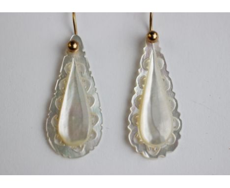 A pair of mother of pearl earrings, each designed as a pear shaped drop with carved and pierced border, yellow metal hoop fit