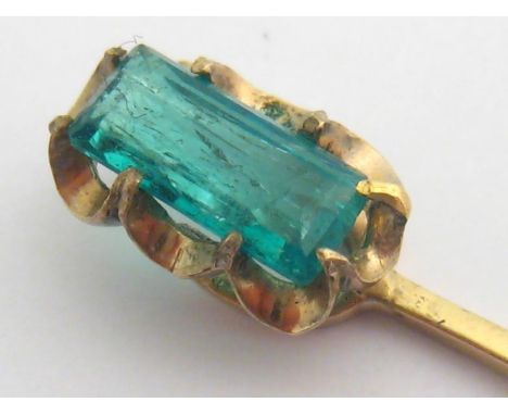 An emerald stick pin, the rectangular cut stone 9.3 x 4.3mm, mounted in yellow metal (tests14 carat gold), 1.8gms 