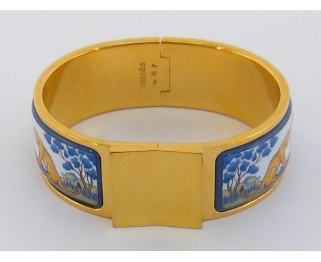 HERMES, a gold plated and enamel bangle, with lion and lioness design, twist release, signed and maker’s cartouche within, th