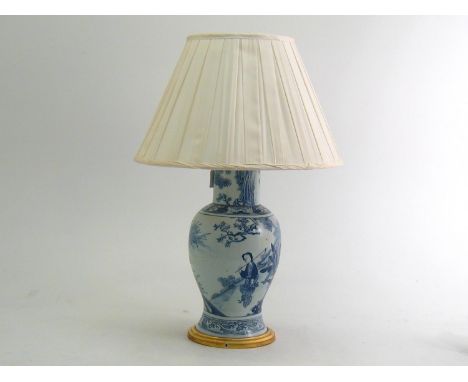 A large blue and white Chinese baluster shaped porcelain table lamp with figures at a table on gilt base with braided flex an