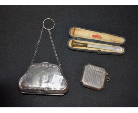 A silver purse, Birmingham hallmarks; a silver vesta case, 1920; a mother of pearl an white metal cigarette holder, cased (3)