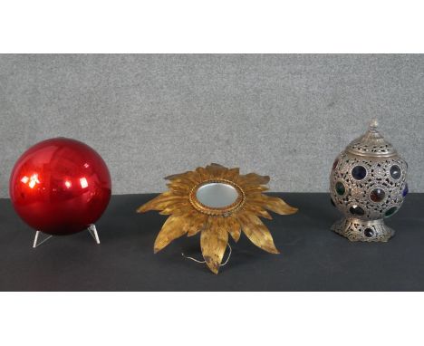A Moroccan style coloured glass and brass lantern, a large red foil blown glass bauble and a gilt metal sun design wall light
