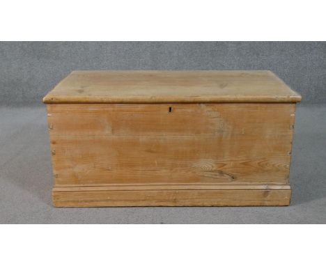 A 19th century pine travelling trunk fitted with candle box and twin metal carrying handles on a plinth base. H.44 W.101 D.47