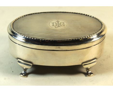A George V hallmarked silver jewellery casket of oval formThe cover having engine turned decoration with engraved initials DJ