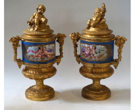 A pair of reproduction gilt metal and hand-painted twin handled urn vasesEach having cherub finials above hand-painted panel 